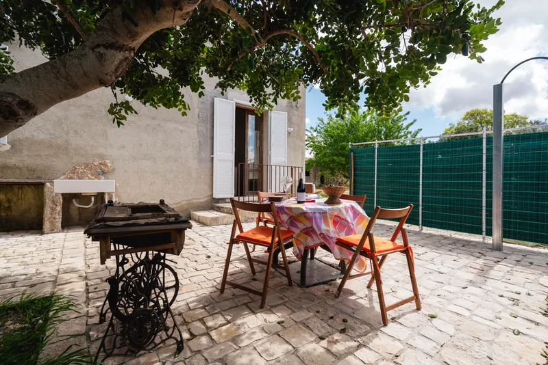 Tavolo apparecchiato e sedie colorate nel cortile sotto un albero